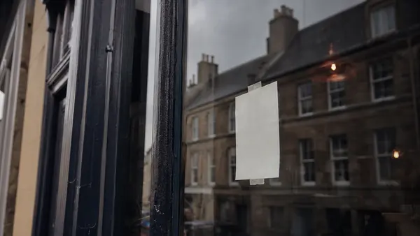 A handwritten shop notice taped inside a window on a Scottish high street.
