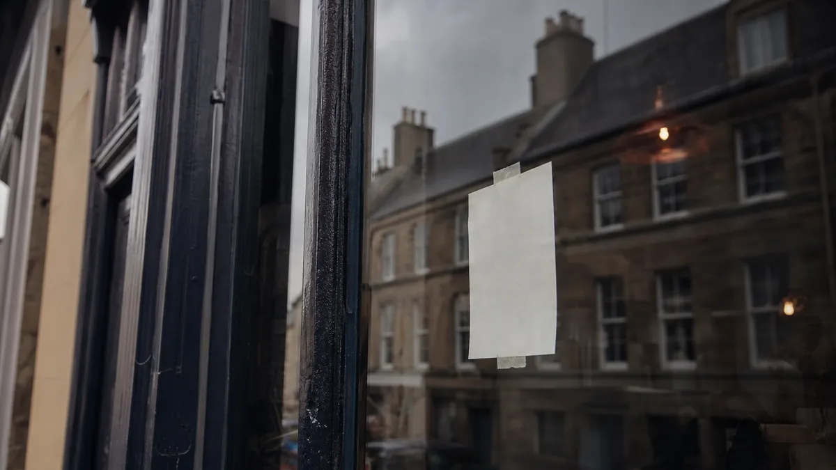A handwritten shop notice taped inside a window on a Scottish high street.