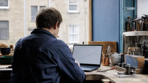 A small business owner reviewing search statistics on a laptop in a workshop