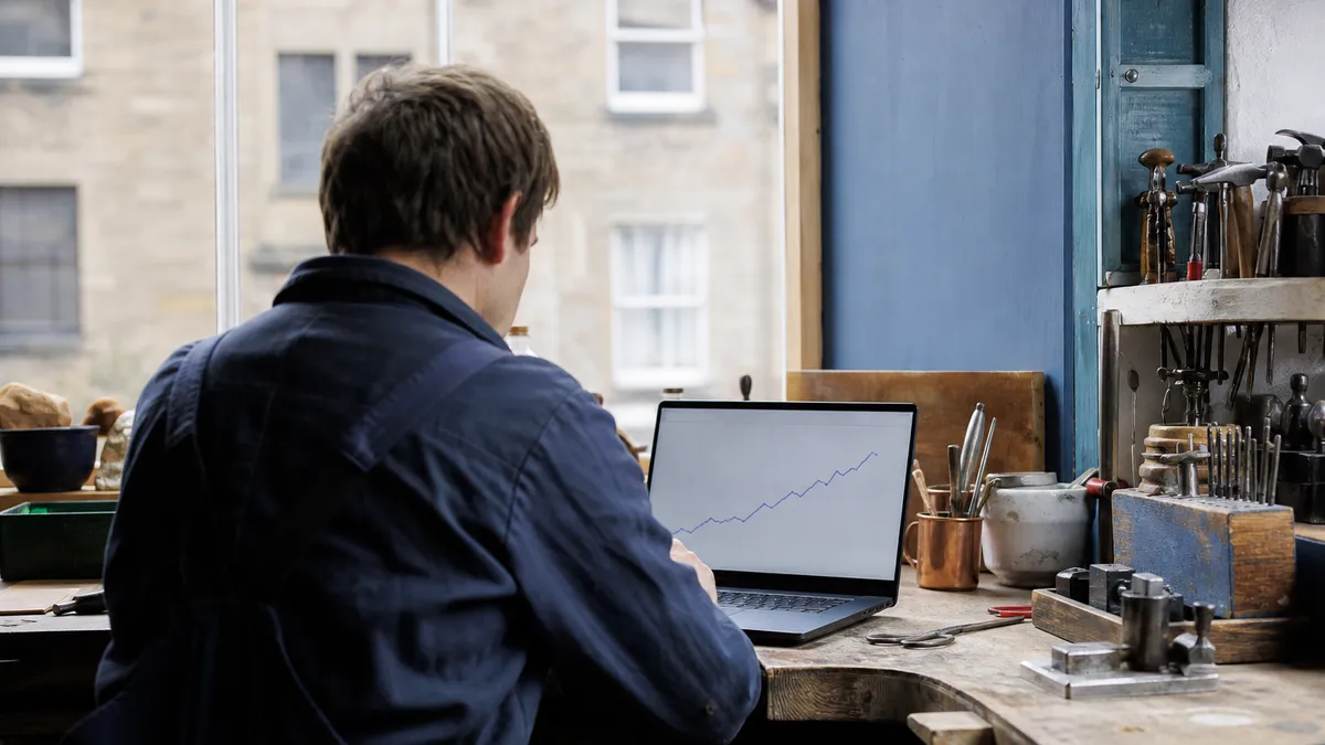 A small business owner reviewing search statistics on a laptop in a workshop